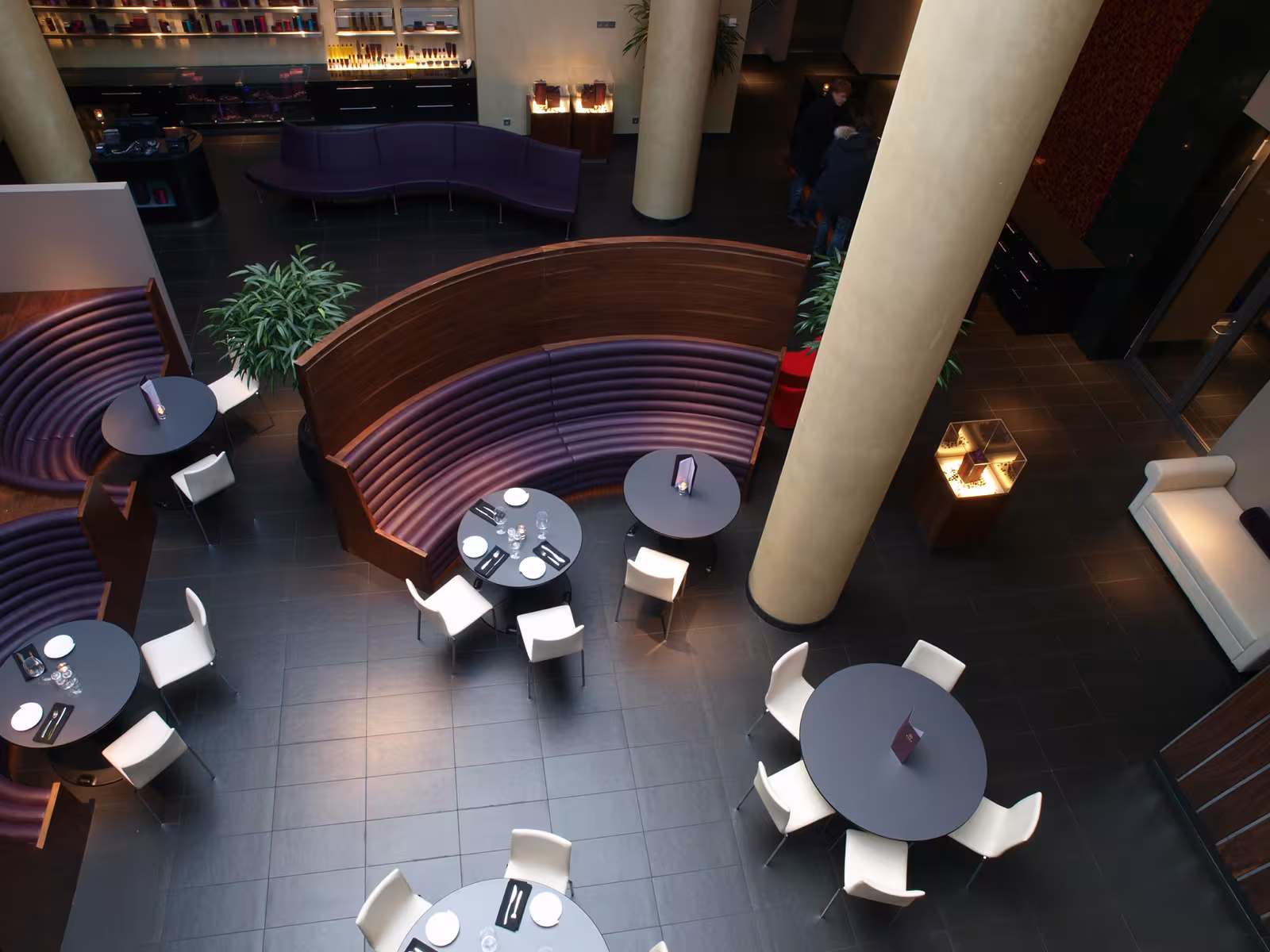 Overhead view of the spa lounge area featuring curved purple velvet seating and dark tiled flooring.