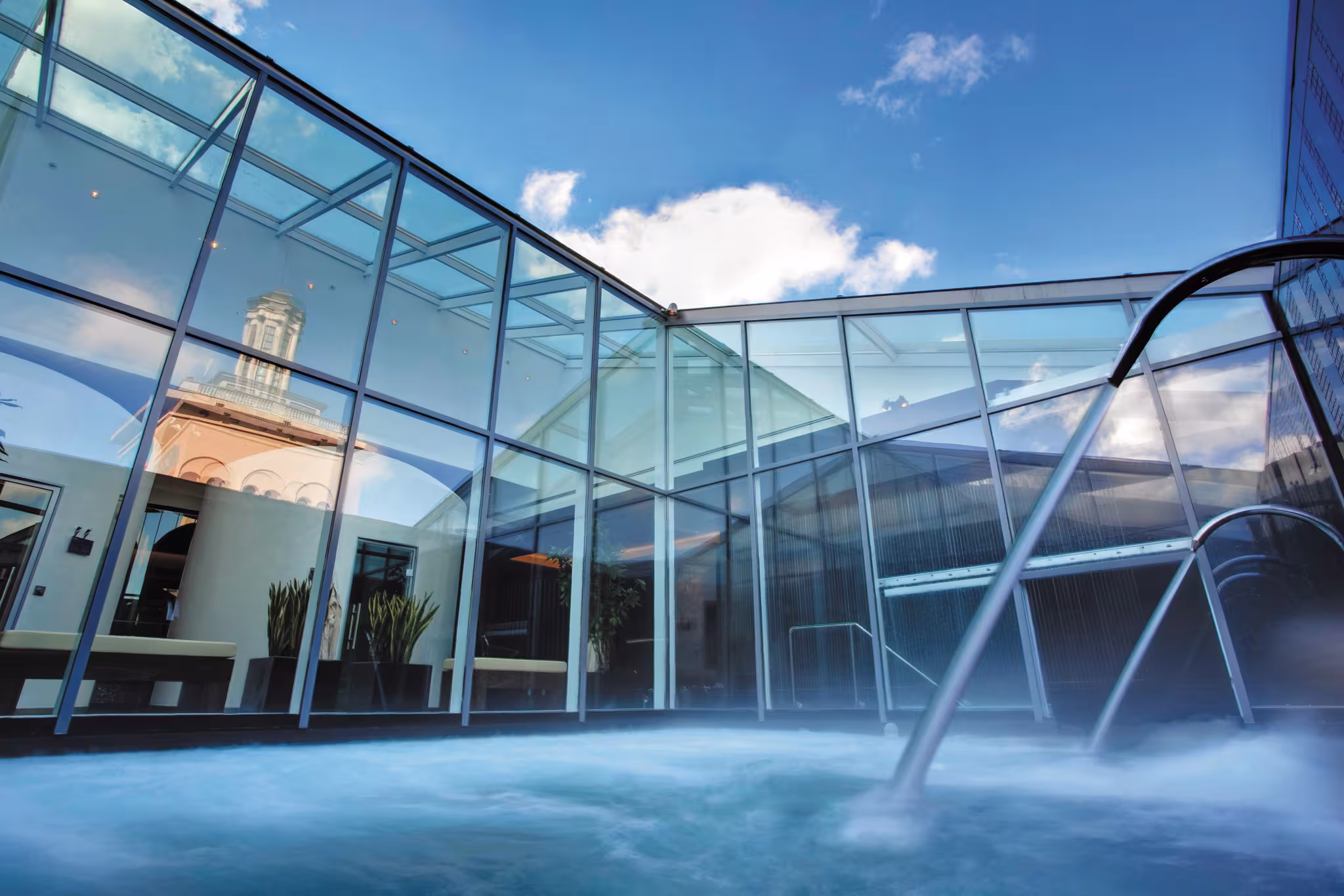 Rooftop vitality pool at E’SPA Riga featuring glass walls with reflections of the surrounding historic city architecture.