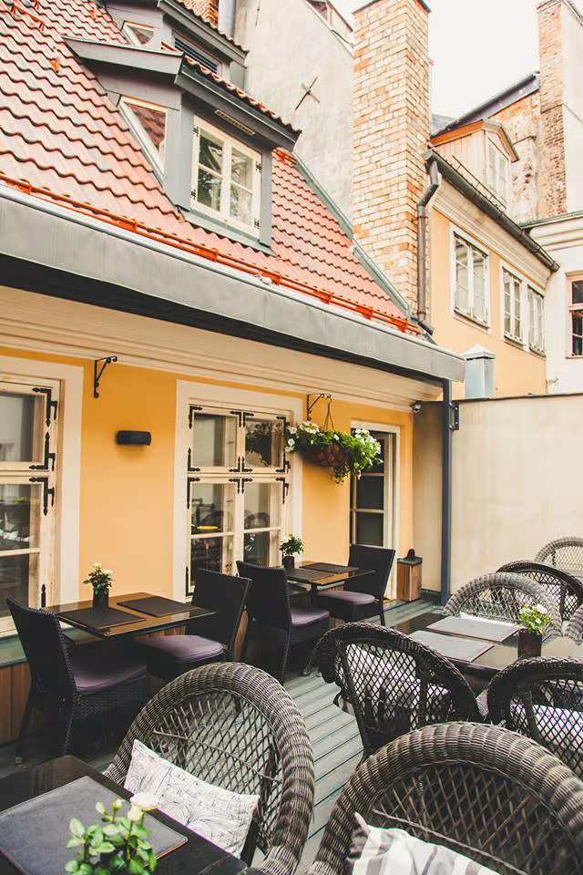 Cozy outdoor roof terrace dining area at 6 Skārņu Street, surrounded by historic Old Town walls and red tiled roofs.