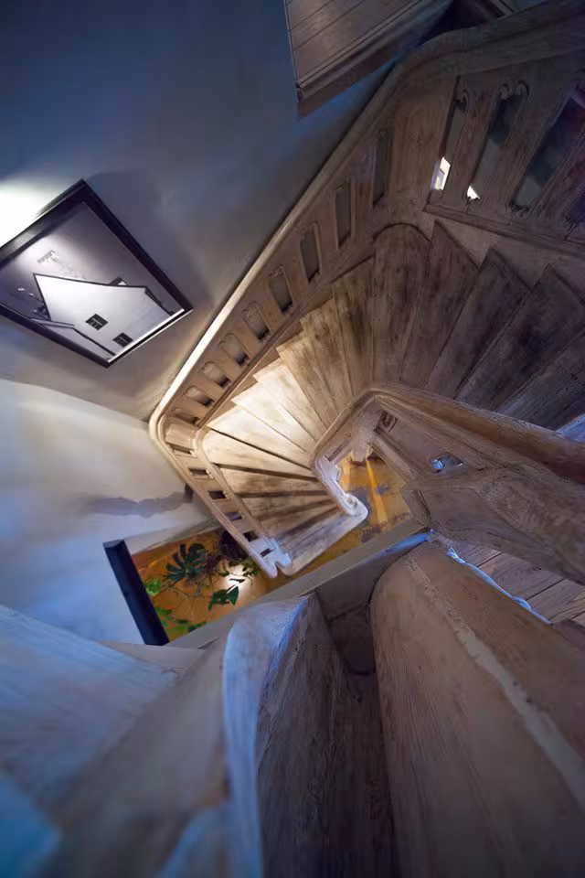Top-down view of the restored original wooden spiral staircase, highlighting the preserved texture and craftsmanship of the 15th-century structure.