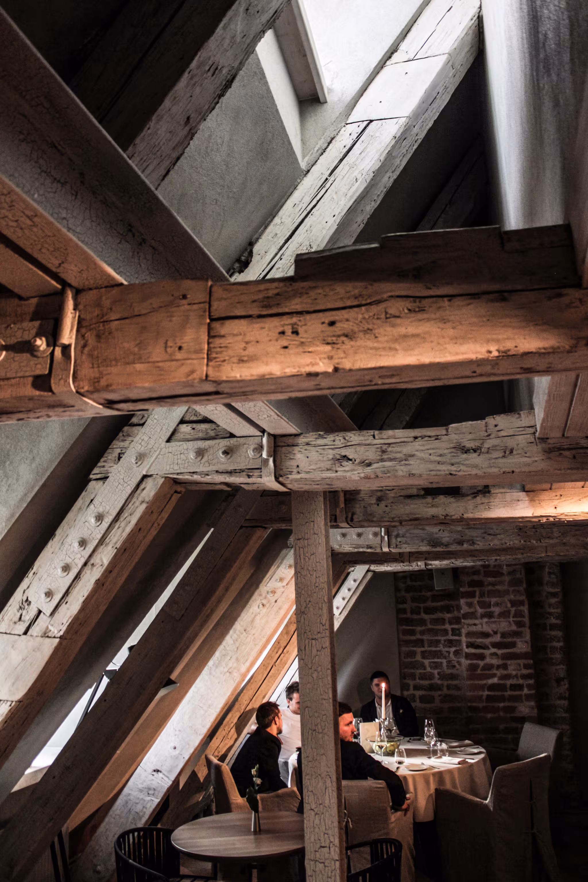Close-up of the preserved medieval timber roof structure, showcasing historic carpentry details above the modern restaurant seating.