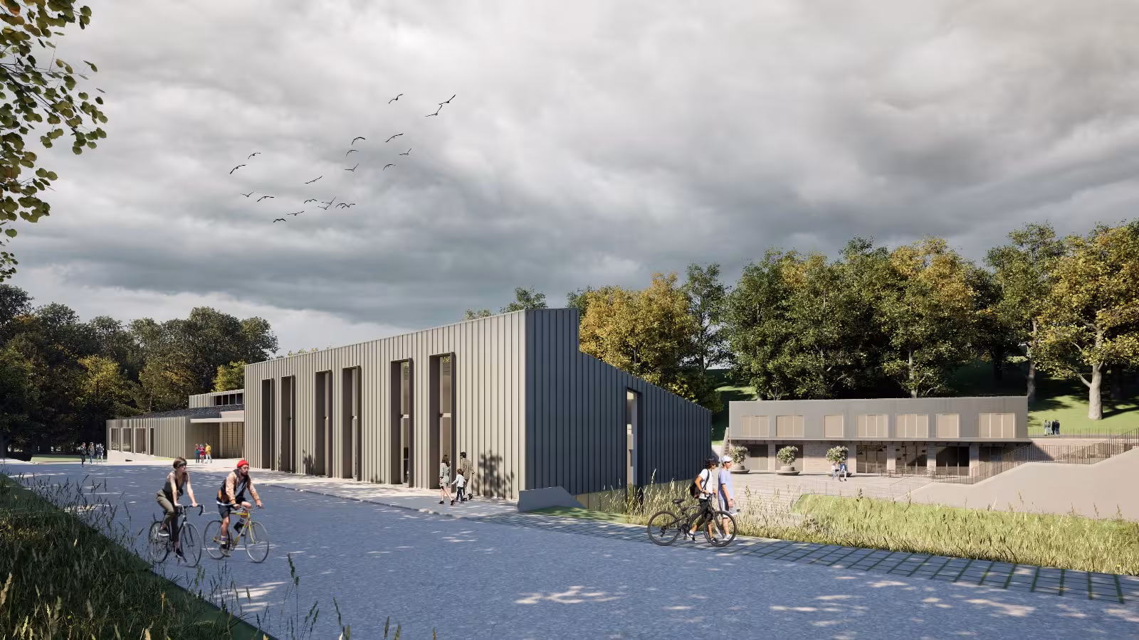 Active public realm in Smiltene Community Quarter with cycling paths and modern industrial-style buildings featuring grey vertical cladding.
