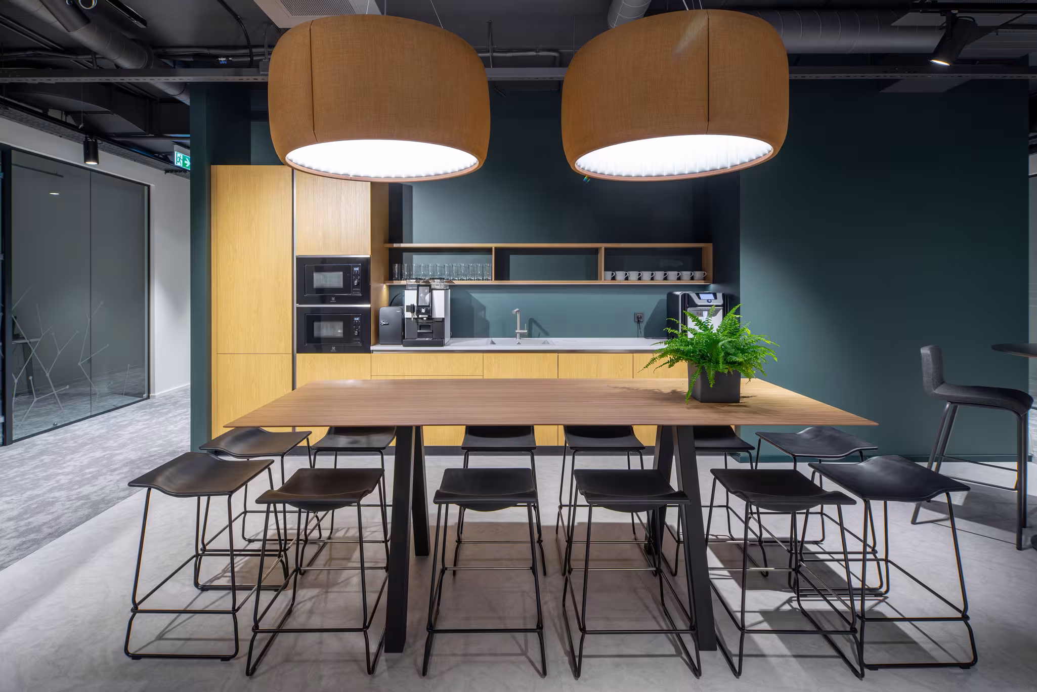 Detail of the communal kitchen island with industrial black stools and warm lighting.