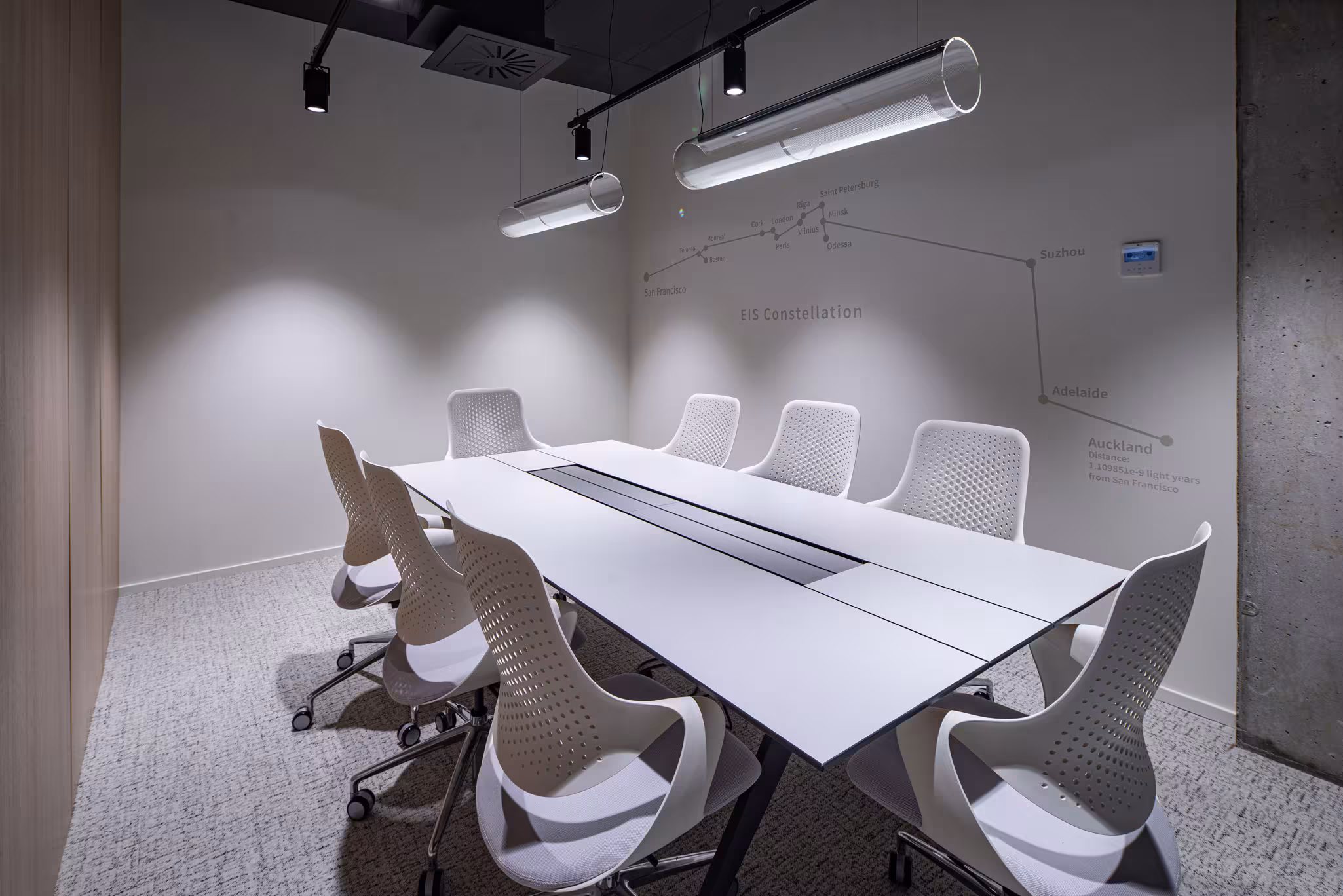 Modern meeting room featuring white ergonomic chairs, a central table with connectivity, and custom linear lighting.