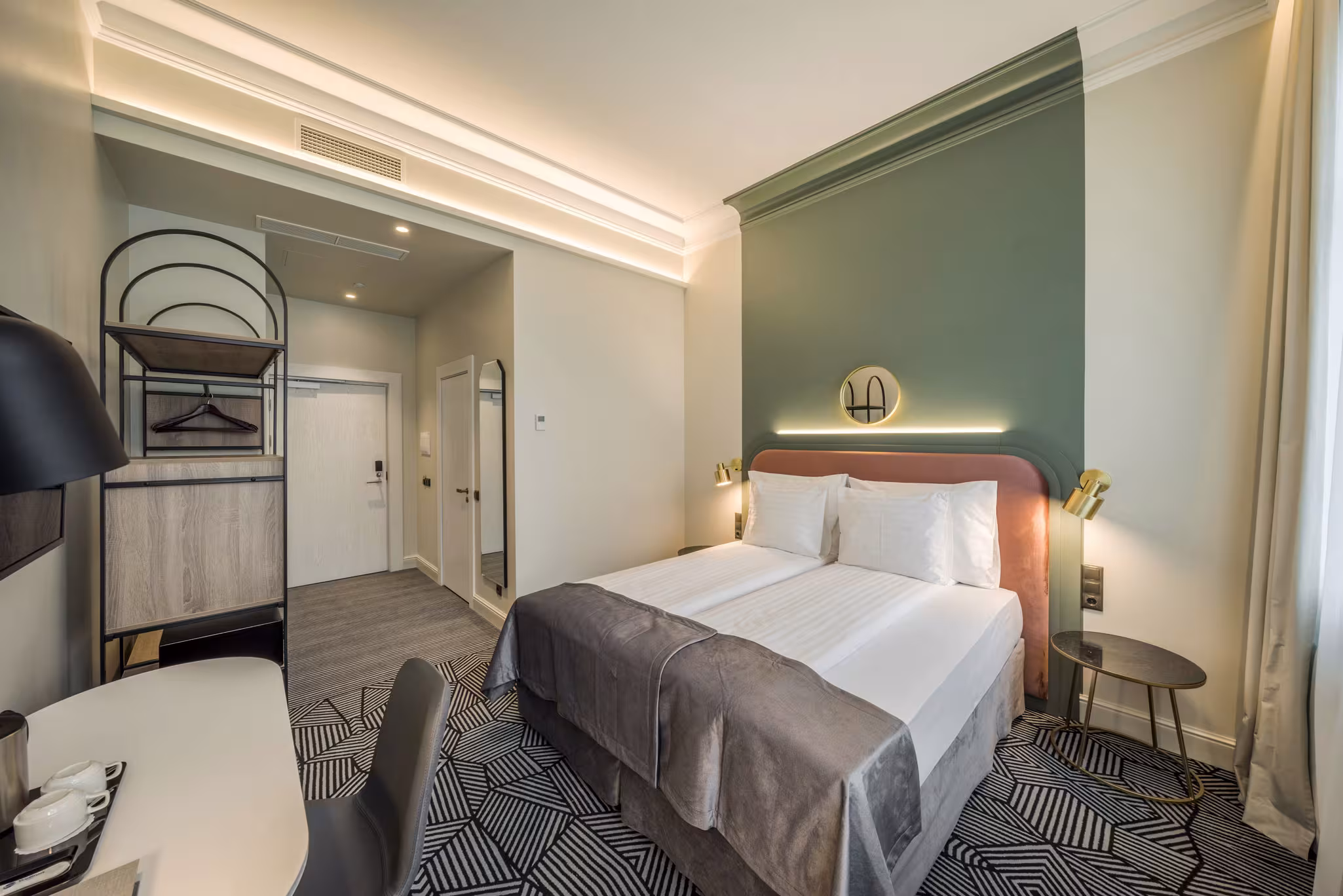 Modern Riverside SPA Hotel room with a double bed, green accent wall, and desk.