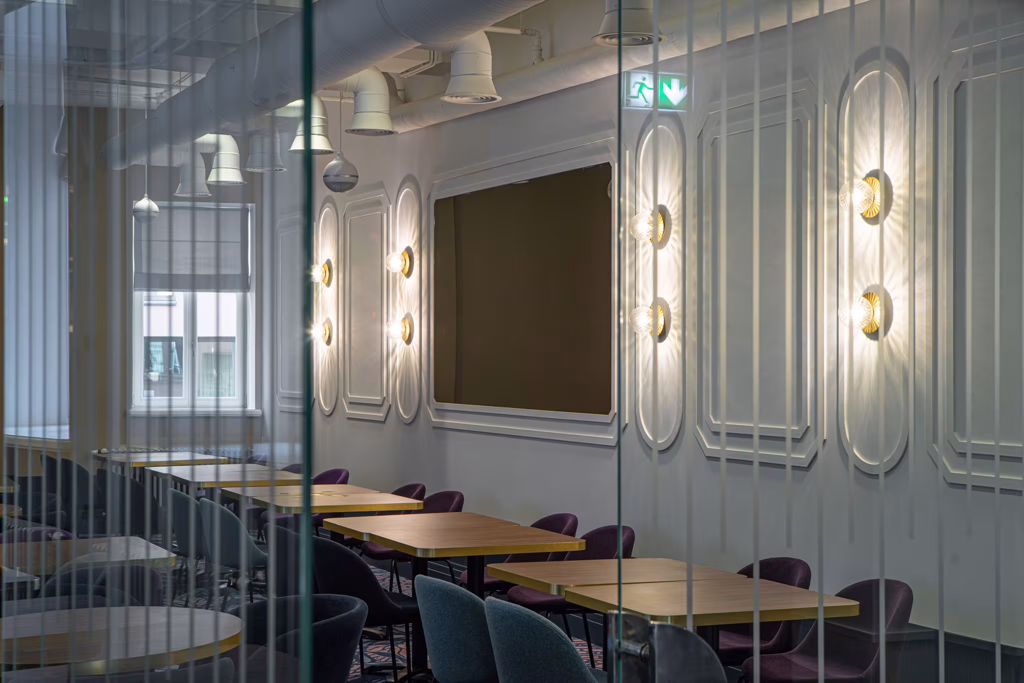 Elegant dining room at Riverside SPA Hotel with modern tables and purple chairs, seen through glass.